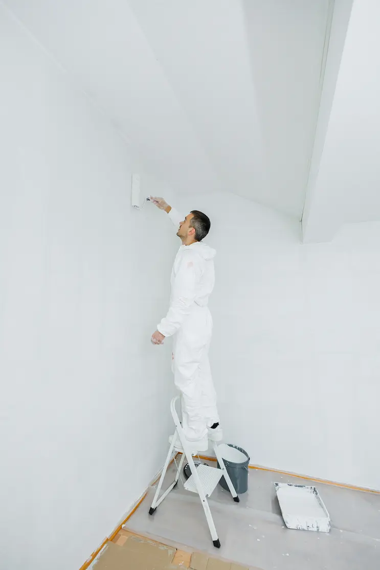 man-white-uniform-with-roller-his-hand-paints-ceiling-white-home-renovation-premises